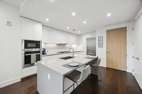 a kitchen with a sink stainless steel appliances and wooden floor