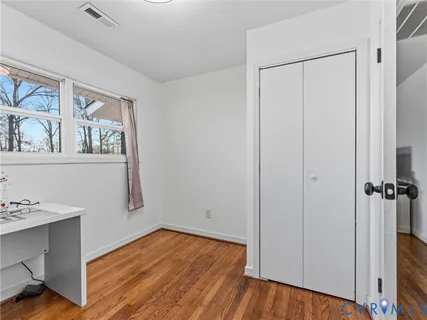a view of a hallway with wooden floor and closet