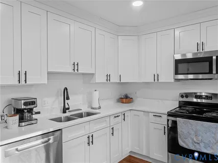 a kitchen with stainless steel appliances granite countertop white cabinets a sink and a stove