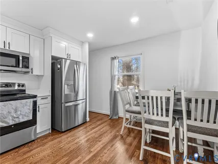 a kitchen with wooden floors stainless steel appliances and a window