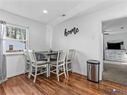a dining room with furniture wooden floor a rug and a painting