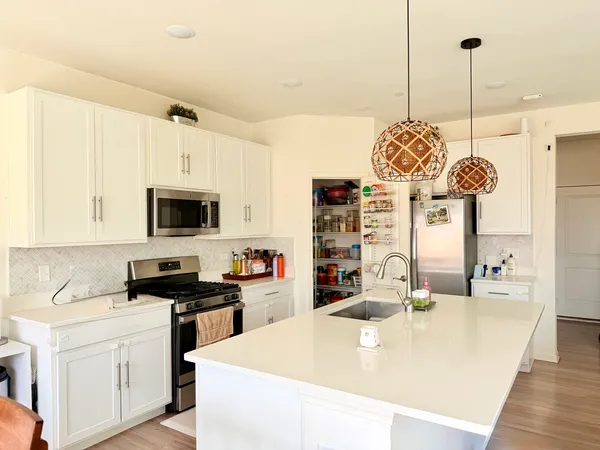 a kitchen with stainless steel appliances kitchen island granite countertop a sink a stove and a wooden floors