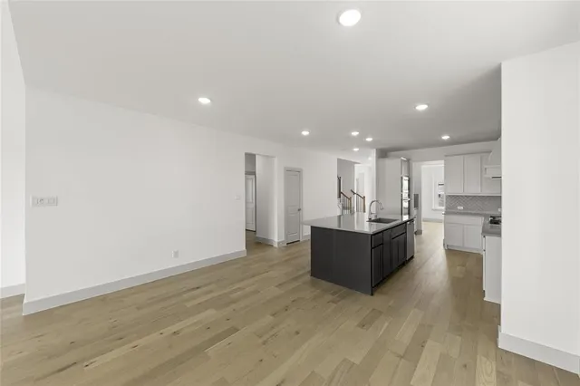 a living room with hard wood floors and kitchen view