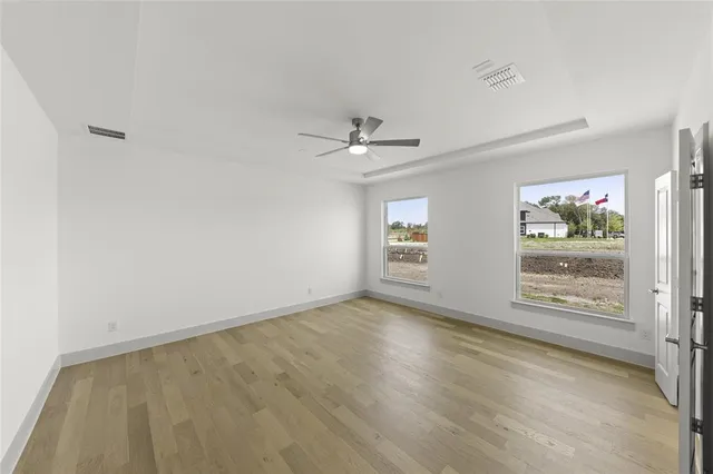 an empty room with windows and ceiling fan