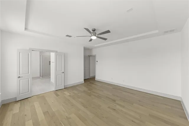 wooden floor in an empty room with a ceiling fan