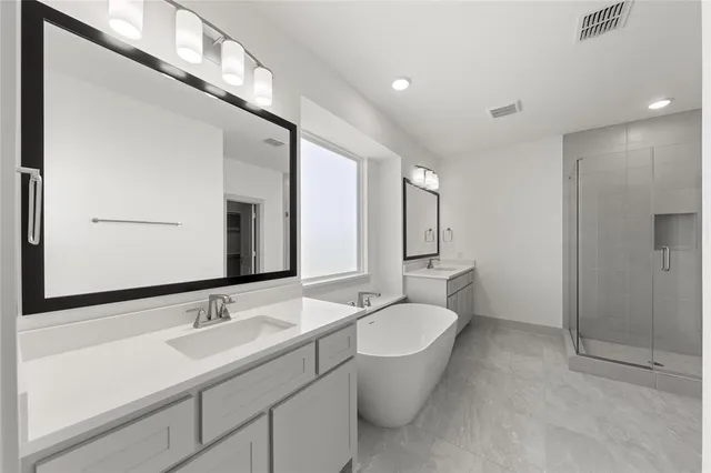 a bathroom with a double vanity sink a large mirror and a bathtub