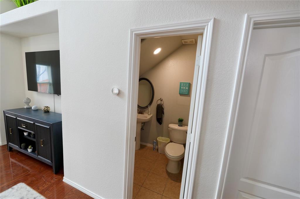 8404 Timberbrook Lane Dallas, TX 75249 - Photo 6 of 32 a bathroom with a toilet a sink and mirror