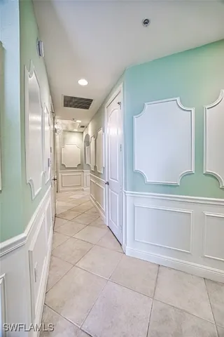 a view of a hallway with stainless steel appliances lots of white cabinets