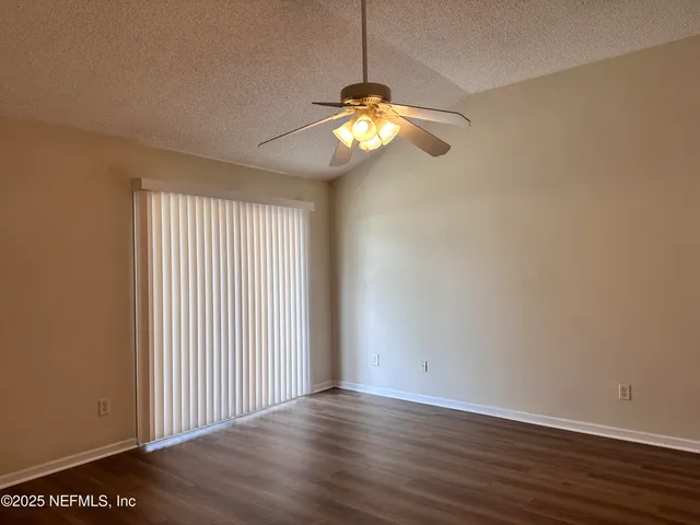 a view of an empty room with wooden floor and windows