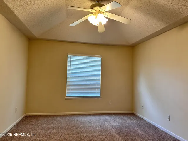 an empty room with a window and a ceiling fan