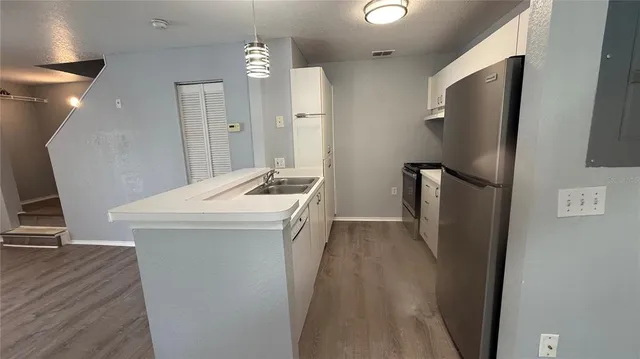 a kitchen with stainless steel appliances a refrigerator a sink a stove and white cabinets