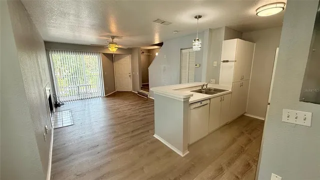 a view of a kitchen with refrigerator and wooden floor