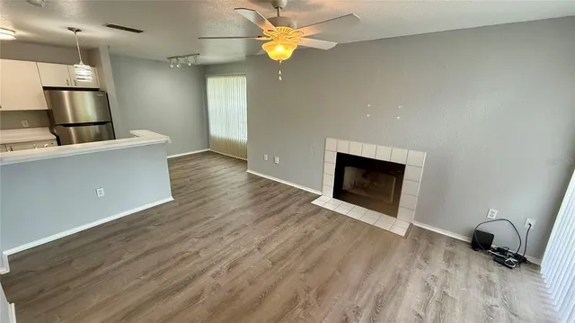 a view of a livingroom with a fireplace a ceiling fan and wooden floor