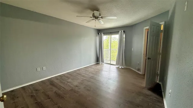 an empty room with wooden floor and a ceiling fan