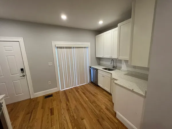 a kitchen with a sink a stove cabinets and wooden floor
