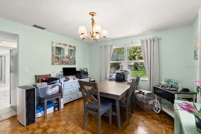 a dining room with wooden floor a chandelier a wooden table and chairs