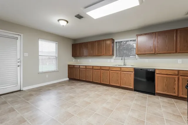 an empty room with ceiling fan and windows