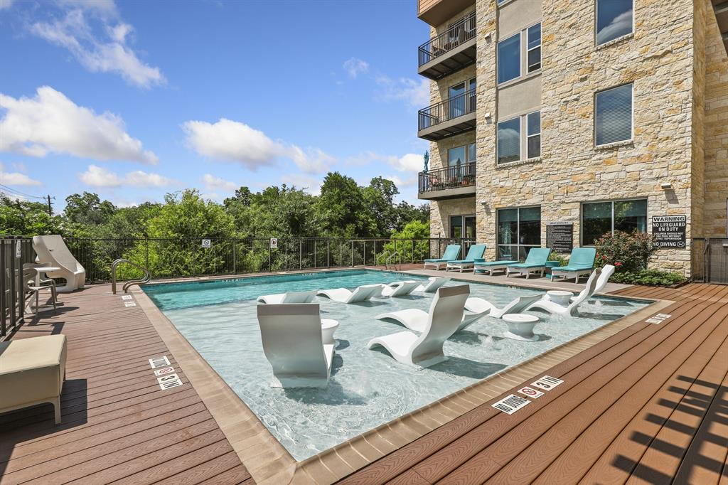 1900 Barton Springs Road, Unit 3013 Austin, TX 78704 - Photo 1 of 27 An inviting outdoor pool with integrated loungers offers a refreshing retreat next to a stone-clad building.