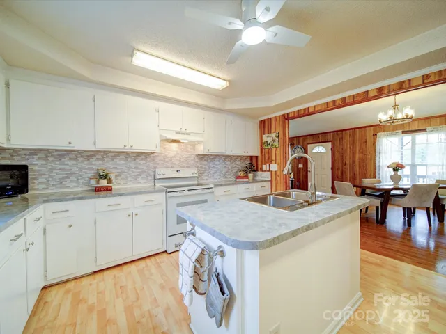 a kitchen with stainless steel appliances granite countertop a stove top oven a sink a dining table and chairs with the cabinets