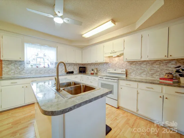 a kitchen with granite countertop a sink a counter space appliances and cabinets