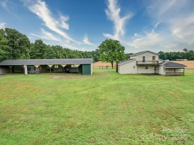 a view of a house with a big yard and large trees