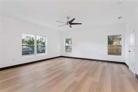 an empty room with wooden floor and windows
