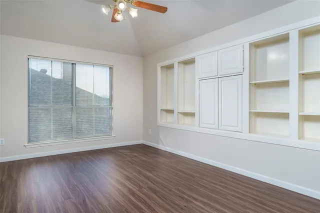 an empty room with wooden floor and windows with curtains view