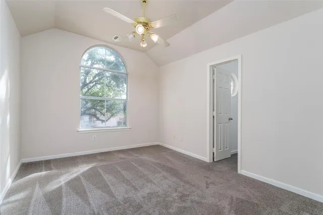 an empty room with windows and ceiling fan