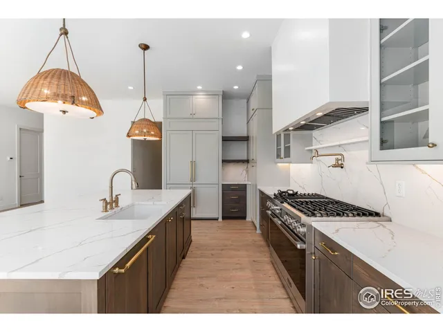 a kitchen with stainless steel appliances granite countertop a sink a stove and a wooden floors