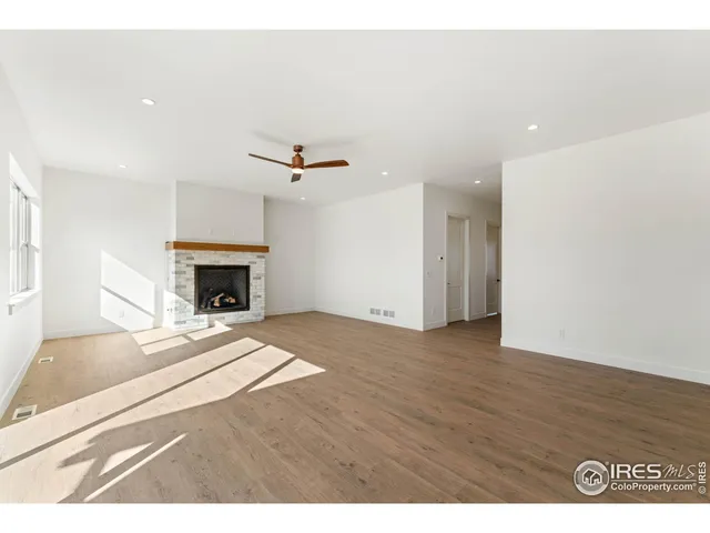 a view of an empty room with wooden floor fireplace and a window
