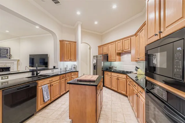 a large kitchen with stainless steel appliances granite countertop a stove top oven a sink dishwasher a dining table and chairs with wooden floor