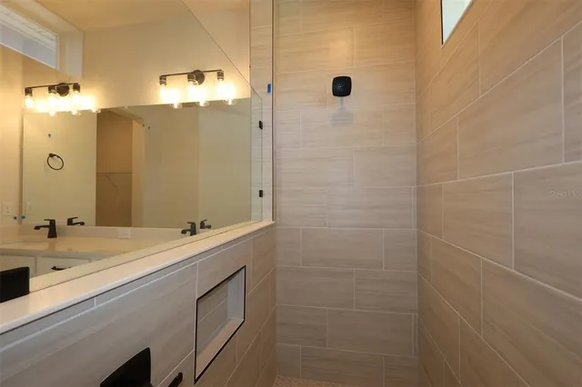a bathroom with a double vanity sink a large mirror and shower