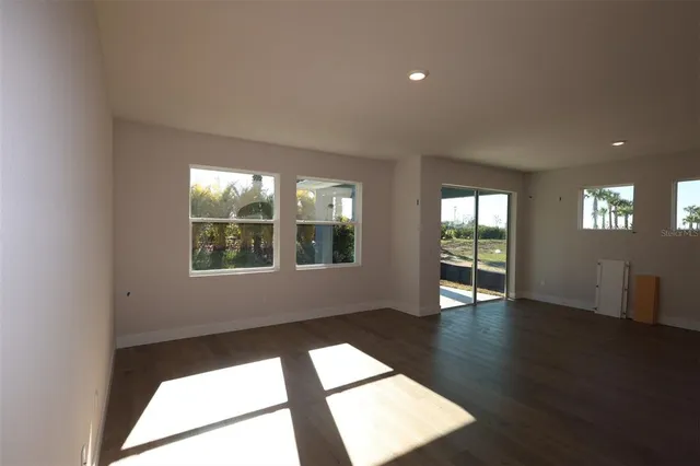 a view of an empty room with wooden floor and windows