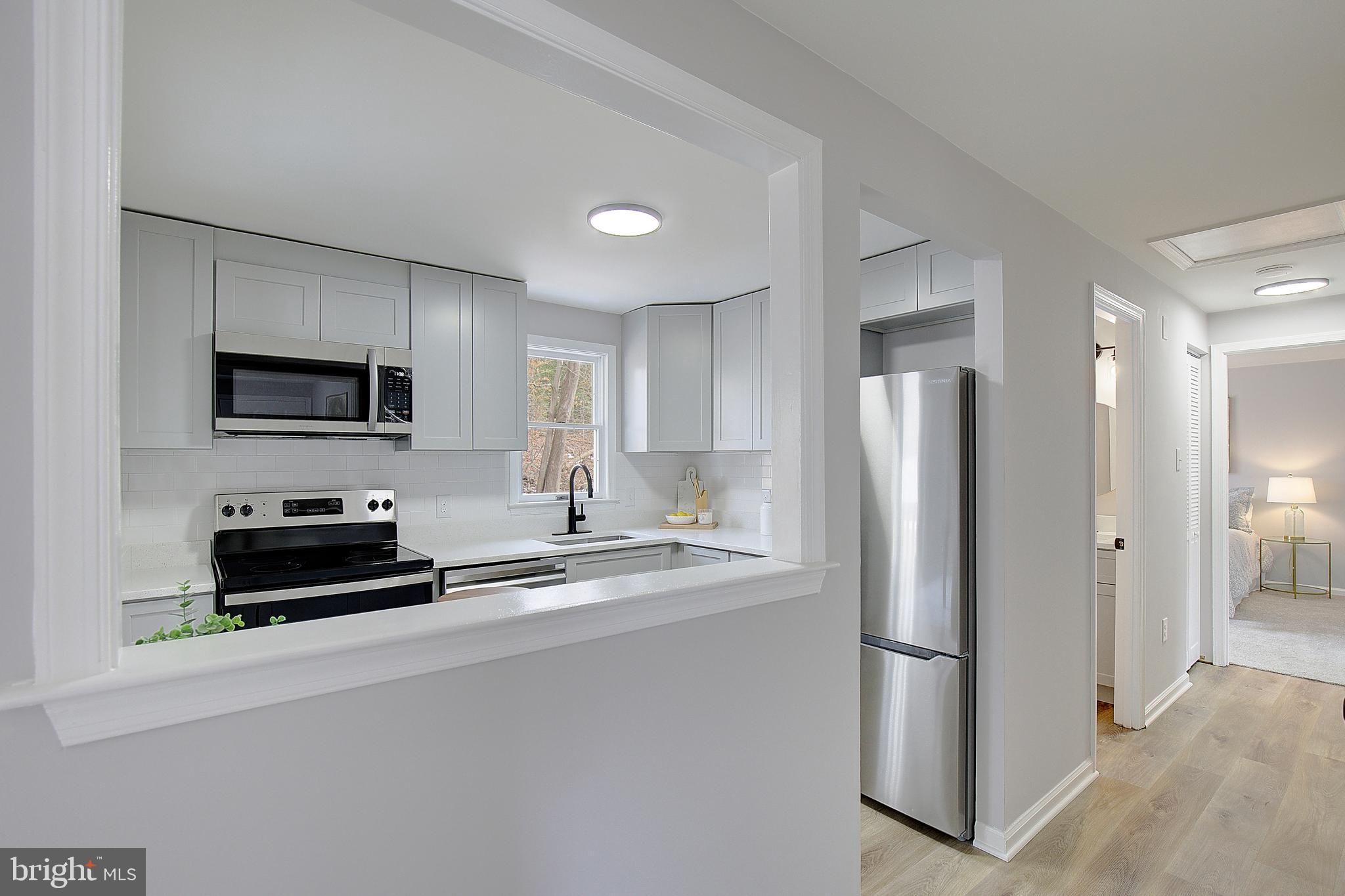 12070 Rousby Hall Road Lusby, MD 20657 - Photo 10 of 36 a kitchen with refrigerator a stove a microwave and cabinets