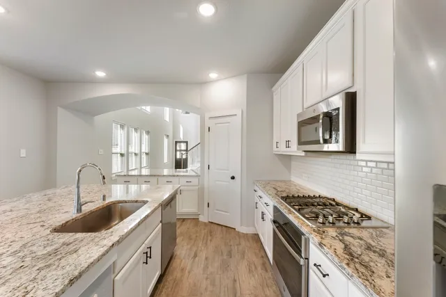 a kitchen with granite countertop a sink stove and cabinets