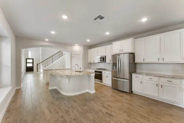 a kitchen with stainless steel appliances a refrigerator and a stove top oven