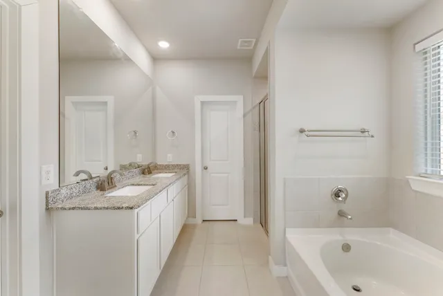 a bathroom with a granite countertop tub sink and mirror