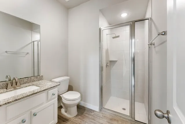 a bathroom with a granite countertop sink toilet a mirror and shower