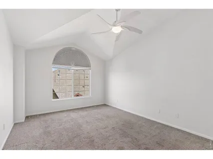 an empty room with windows and chandelier fan