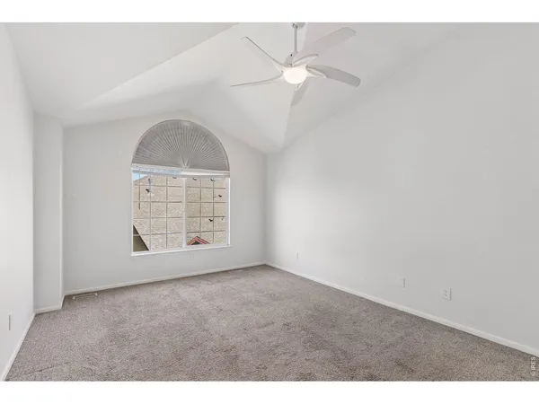 an empty room with windows and chandelier fan
