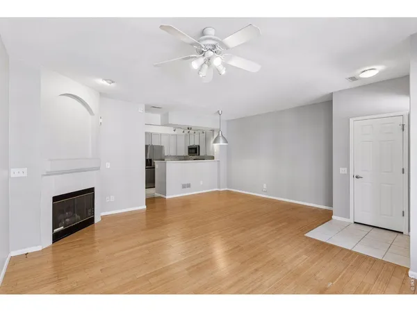 a view of empty room with kitchen and fireplace