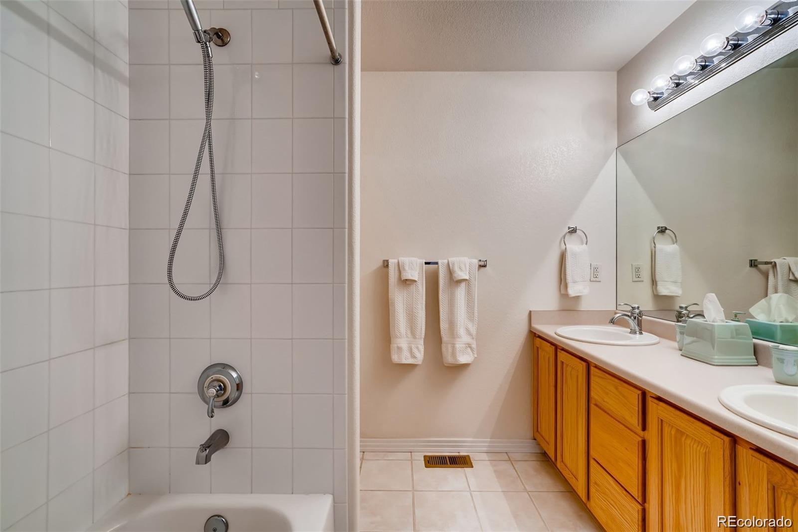 935 Green Gables Circle Bennett, CO 80102 - Photo 25 of 34 a bathroom with a double vanity sink a mirror and shower