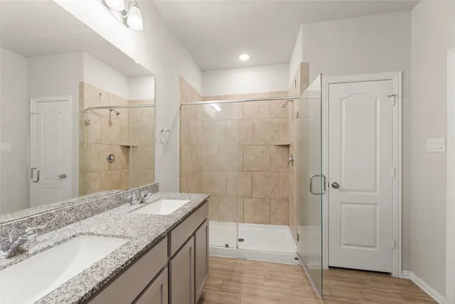 a bathroom with a granite countertop sink a mirror and a shower