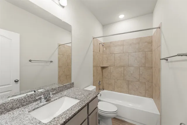 a bathroom with a granite countertop sink toilet mirror and bathtub