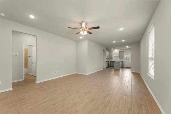 a view of a livingroom with a kitchen stove a refrigerator with wooden floor and a ceiling fan