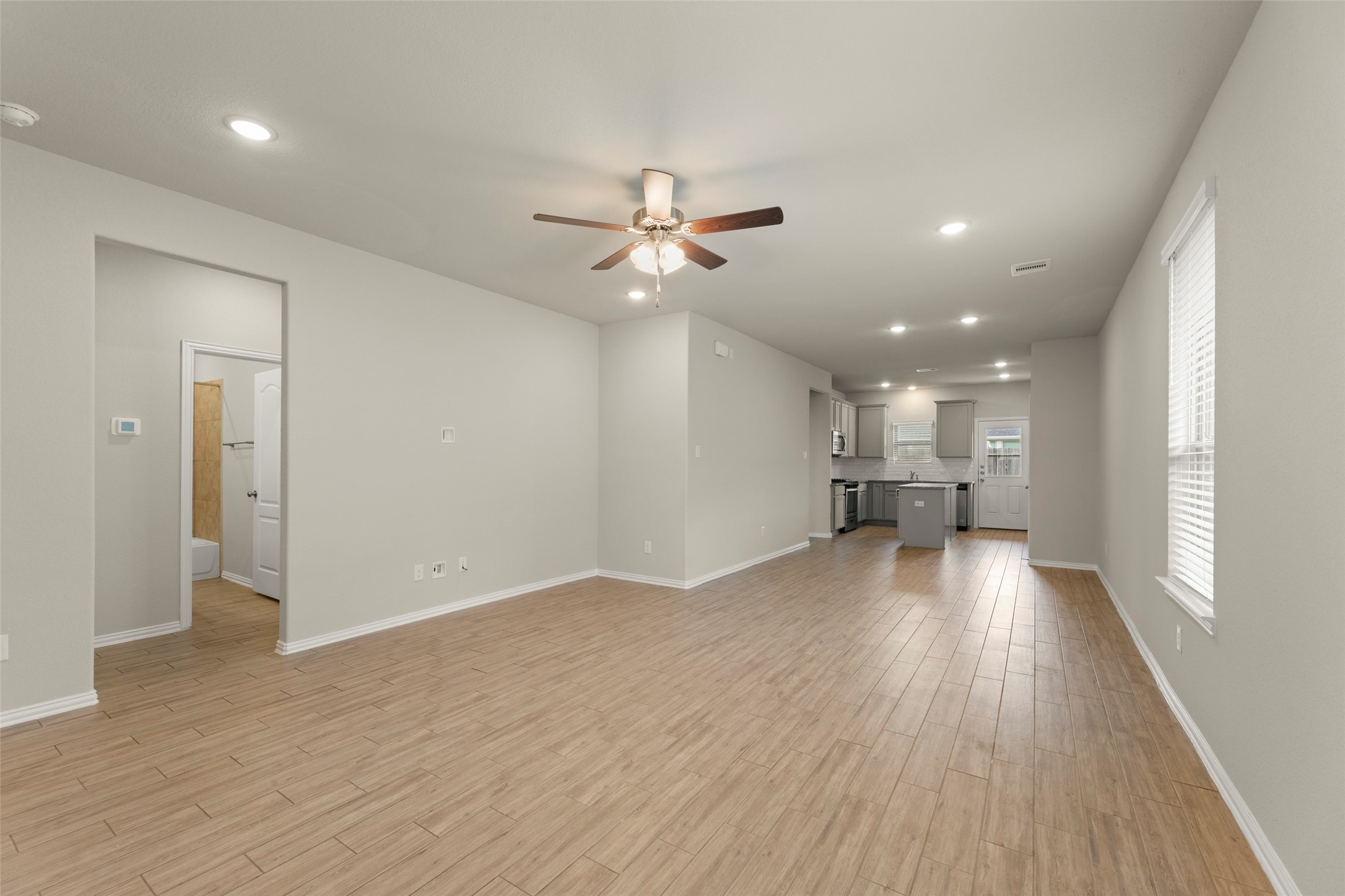 31322 Conover Drive Fulshear, TX 77441 - Photo 8 of 38 a view of a livingroom with a kitchen stove a refrigerator with wooden floor and a ceiling fan