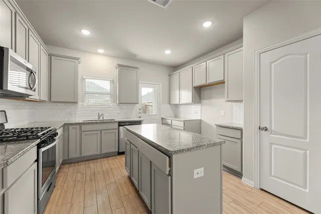 a kitchen with kitchen island granite countertop a sink stove and cabinets