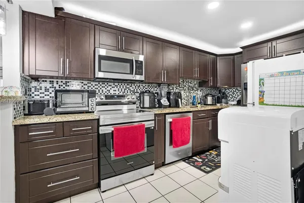 a kitchen with stainless steel appliances kitchen island granite countertop a stove a sink and a microwave