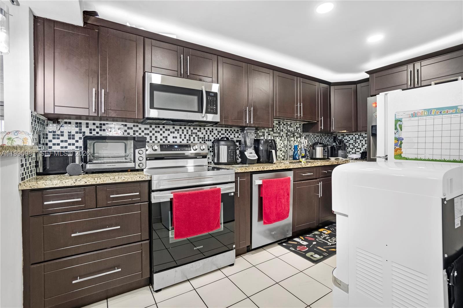 9403 Southwest 76th Street, Unit Y17 Miami, FL 33173 - Photo 2 of 30 a kitchen with stainless steel appliances kitchen island granite countertop a stove a sink and a microwave
