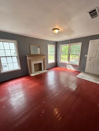 an empty room with windows and fireplace